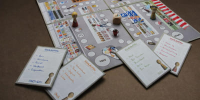 Spielbrett mit Spielfiguren, Würfel und mehreren Einkaufskarten; jede Karte zeigt eine charaktertypische Einkaufsliste.